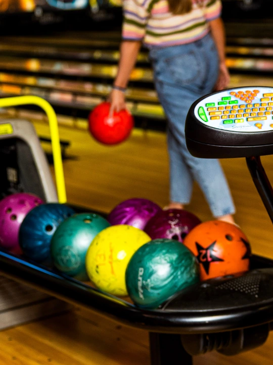 girl behind bowling console about to launch bowling ball